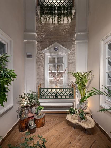 The completed open-to-sky shaft in the Kaira residence. Adorned with rubble masonry and classical mouldings, this architectural feature brings light and ventilation deep into the home, creating a tranquil, plant-filled corridor.