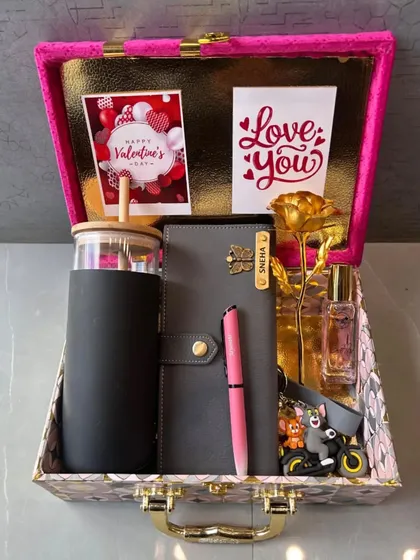 A stylish and practical gift set for her, presented in a beautiful suitcase-style box. This hamper includes a personalized tumbler, diary, pen, and keychain, along with a golden rose and perfume.