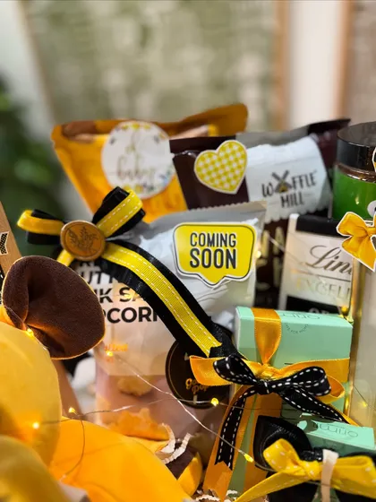A peek at the goodies inside, including gourmet popcorn, Lindt chocolates, and other treats for the mom-to-be, all tied together with the yellow and black bee theme.