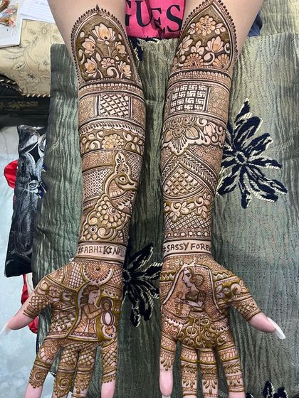 We can even include your wedding hashtag directly in the design. This bridal mehndi features "#ABHIKISASSY" and "FOREVER" alongside beautiful bride and groom portraits.