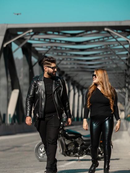 A candid walking shot of the couple on a bridge, sharing a look. The motorcycle in the background adds to the story of their adventurous pre-wedding session.