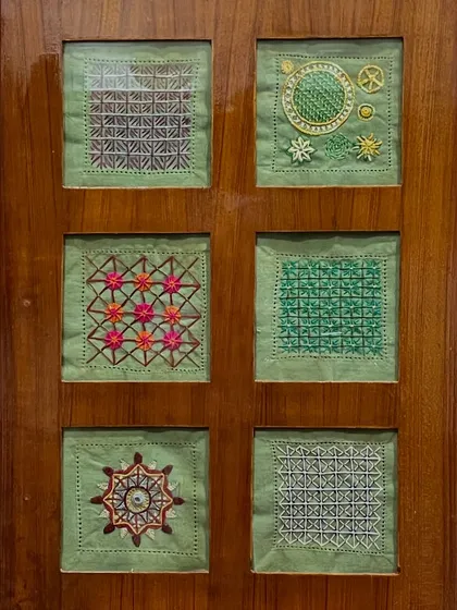 Another set of six framed embroidery samplers, this time on a green background. Each square showcases a different stitch or pattern, celebrating the diversity of the craft.