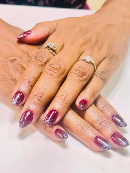 A sophisticated look with deep maroon nails and a silver glitter ombre effect on the tips.