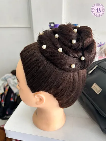 A photo of an elegant high bun with pearl details, demonstrating another classic hairstyle taught in the course.