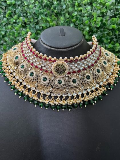 A wide choker from my rental collection, featuring intricate filigree circles with green and red accents. The green bead drops add a finishing touch.