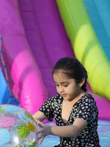 A quiet moment of play amidst the splashing. A young girl enjoys playing with an inflatable ball in the cool water of our summer pool.