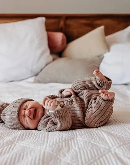 A real-life moment of a baby crying on the bed. We believe in capturing the real and raw emotions of family life, not just the perfect smiles.