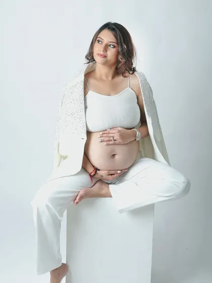 A powerful solo portrait of a mother to be in a chic all white outfit. The open blazer and confident pose celebrate her strength and beauty during pregnancy.
