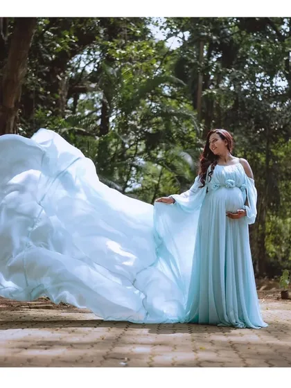 This shot is pure magic. The powder blue flying train gown looks like angel wings in this beautiful garden setting, creating a truly ethereal and unforgettable maternity portrait.