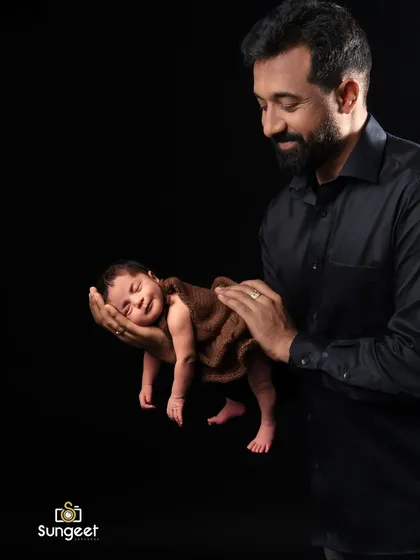 So small and safe in her father's hands. This powerful and creative shot emphasizes just how tiny a newborn is, creating a moving portrait of a father's protective love.