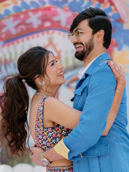 A happy, candid moment between a couple at their Mehendi. The bride's fun and flirty ponytail is perfect for the playful vibe of the event.