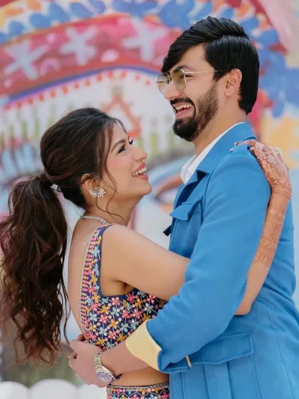 A happy, candid moment between a couple at their Mehendi. The bride's fun and flirty ponytail is perfect for the playful vibe of the event.
