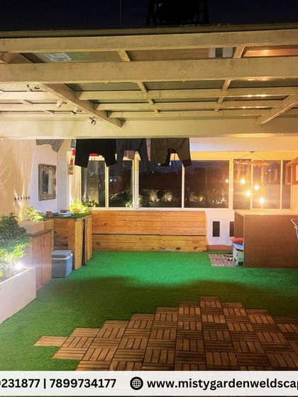 A functional and cozy terrace design, featuring a clothes drying area integrated under the pergola, a wooden bench, and a bar counter, all set on a floor of artificial grass and WPC tiles.