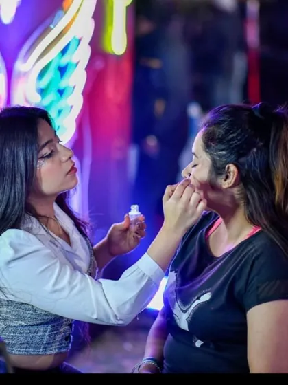 Applying some glitter on a client at a neon-lit event. You can see how the right lighting can make the face art really stand out.