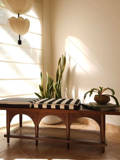 The Kaav bench, a functional and statement piece of furniture ideal for foyer spaces or as additional living room seating. Its arched design and rattan shelf offer both aesthetic appeal and practicality.