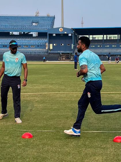 An athlete performs agility drills, weaving through cones on the field. This training improves change-of-direction speed and footwork, which is vital for fielding and running between the wickets.