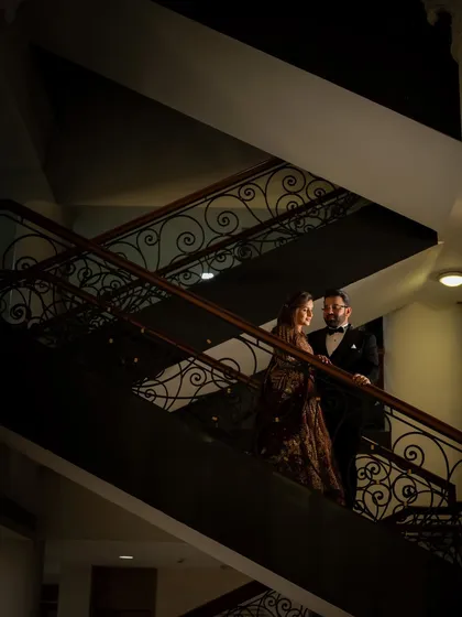 A dramatic, low-light portrait of the couple on a staircase. We use shadows and light to create a moody and cinematic feel.