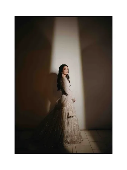 A full-length bridal portrait using a single spotlight for dramatic effect. This technique creates a theatrical, high-fashion look that emphasizes the bride's silhouette and the stunning detail of her gown.