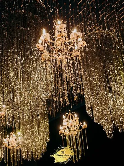To create a ceiling that dazzles, I hung thousands of shimmering tinsel strands interspersed with classic chandeliers. The effect is a breathtaking canopy of light that transforms the entire space into a glamorous ballroom.