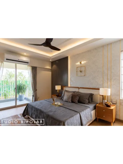 In this bedroom for a Jaipur apartment, a dark grey fluted panel contrasts with a light, textured wallpaper with gold inlay. The design is modern, sophisticated, and full of interesting textures.
