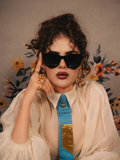 A close-up of the makeup, featuring a bold lip and defined eyes, complemented by statement sunglasses for a chic editorial feel.