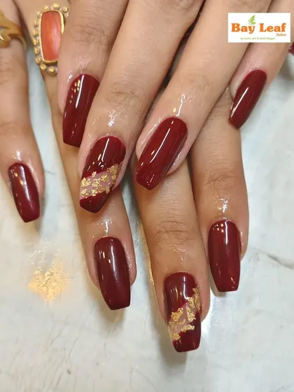 Perfect for a wedding or festive occasion. This design showcases rich, glossy maroon nail extensions with two accent nails featuring delicate gold foil detailing.
