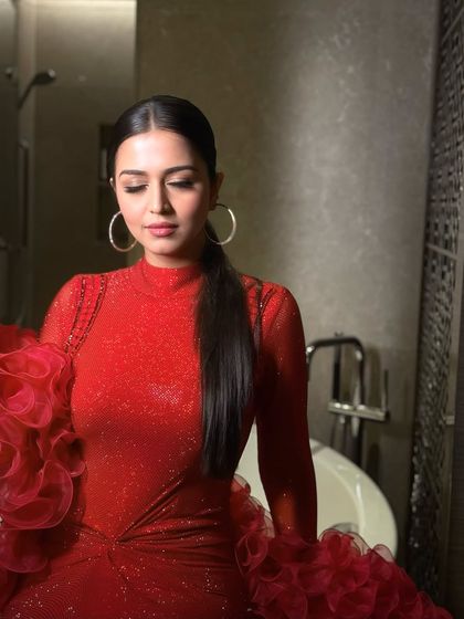 The gold-dusted eyeshadow catches the light beautifully, adding a touch of warmth and sparkle to the dramatic red outfit.