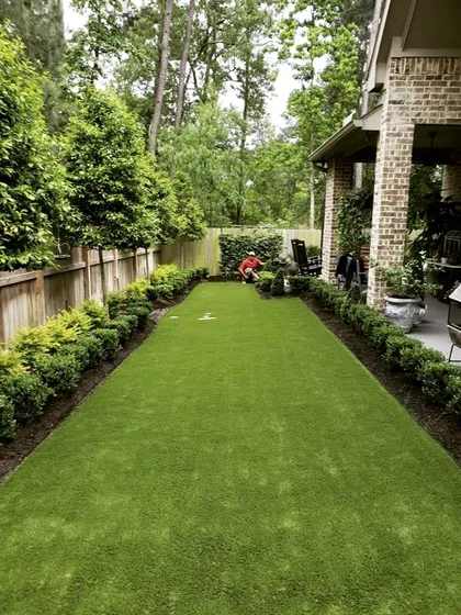 A long, rectangular lawn bordered by neat hedges. This image shows our team at work, demonstrating the care we take in maintaining and perfecting every landscape project.