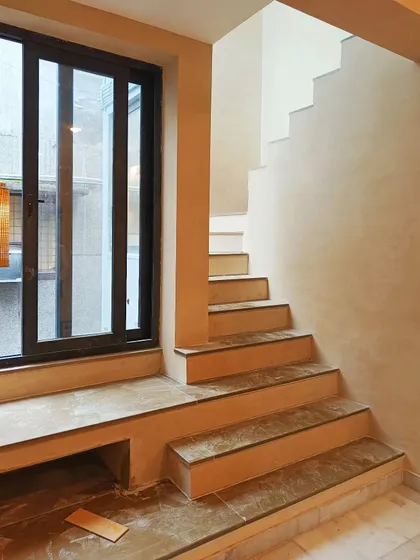 A minimalist residential design in Vasant Kunj, where the focus is purely on the interplay of light, texture, and form. Monochrome stucco walls and clean lines create a serene and sculptural staircase environment.