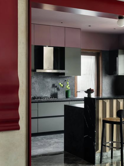 This view into the kitchen highlights the continuity of materials and thoughtful transitions. The dark bronze details and striped breakfast counter add depth, connecting the kitchen seamlessly with the adjoining dining area for a cohesive spatial experience.