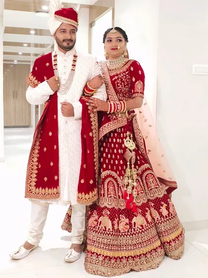 This full-length shot shows how the groom's white and red sherwani is perfectly complemented by the bride's red lehenga. A coordinated look makes for stunning wedding photos.