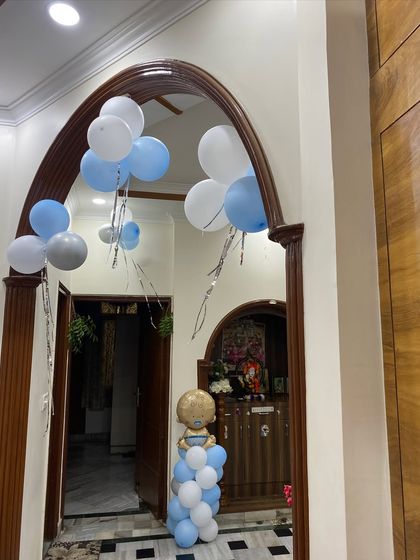 A welcoming entrance for a baby boy's celebration, with balloon bunches and a small balloon pillar featuring a baby-themed foil balloon.