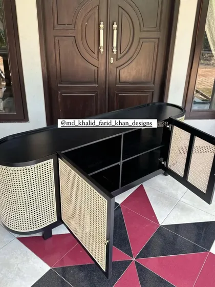 This sleek, oval-shaped console cabinet features a black finish contrasted with natural hand-woven cane doors. The interior reveals ample shelving, making it a perfect custom storage solution for a dining or living room.