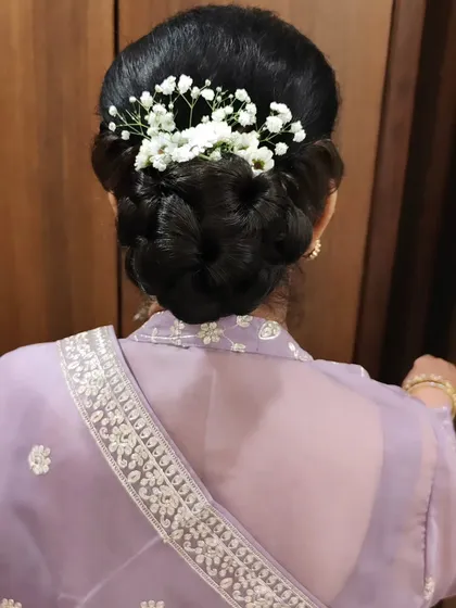 A classic and elegant braided bun, beautifully decorated with fresh baby's breath. This is a timeless hairstyle that works wonderfully for mothers of the bride or for any guest wanting a sophisticated look.