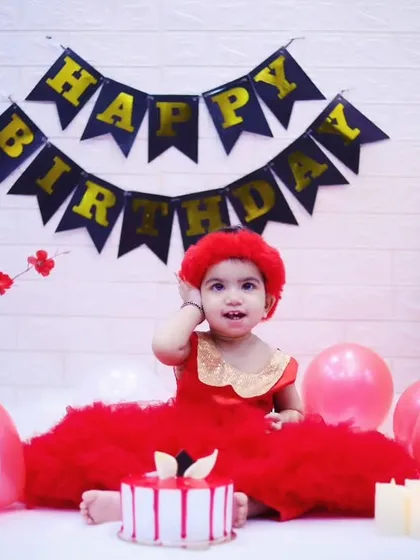 A beautiful first birthday portrait with a cake, balloons, and a 'Happy Birthday' banner. This little princess is ready to celebrate.