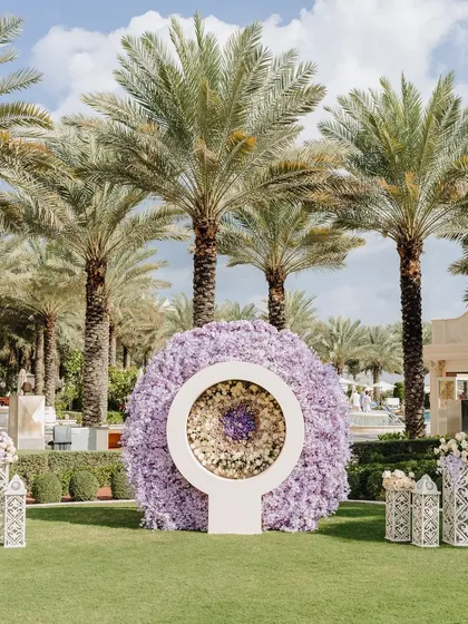 A unique circular floral installation in shades of lavender, serving as a modern and artistic focal point for an outdoor event.