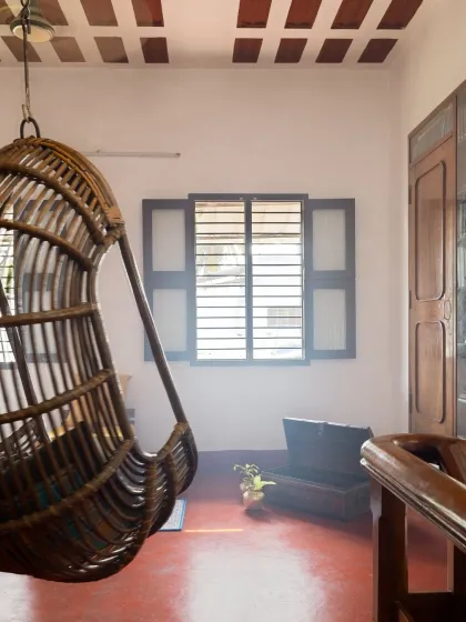 A classic cane swing chair hangs in a sunlit corner, offering a perfect spot for relaxation. The design respects the home's history while creating moments of simple comfort.