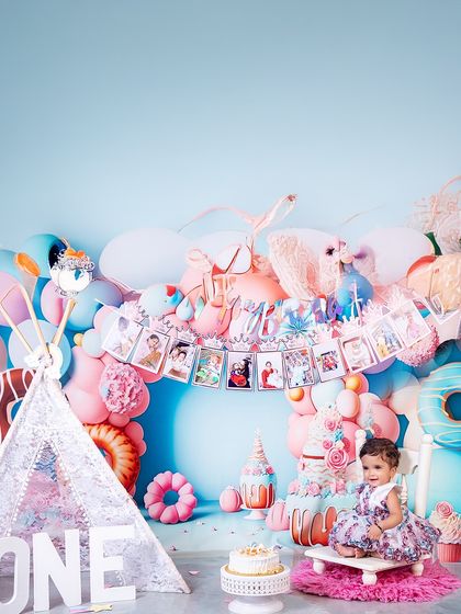 Sitting like a little queen on her throne, this one-year-old is surrounded by a pastel dreamscape. The photo banner above tells the story of her incredible first year.