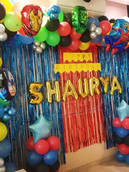 An action-packed Avengers theme birthday party. The decoration features a colorful balloon arch with foil balloons of Iron Man, Hulk, Spider-Man, and Captain America, perfect for a young superhero fan.