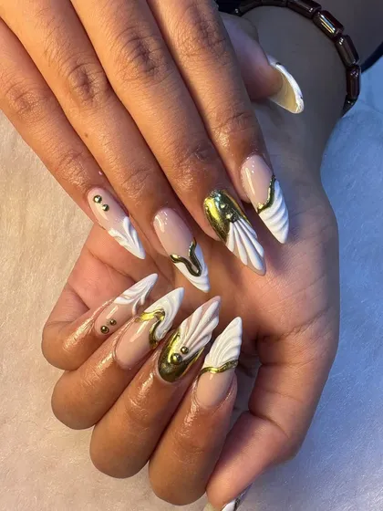 We love creating statement nails like this set featuring sculpted white forms and bold, liquid gold chrome accents. This is the perfect example of how we combine different techniques like 3D art and chrome finish for a truly unique, luxury manicure.