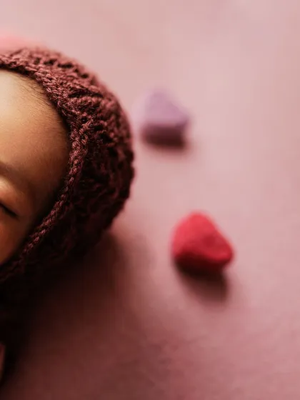 A creative, artistic crop of the baby in the pink bonnet, focusing on the texture and color.