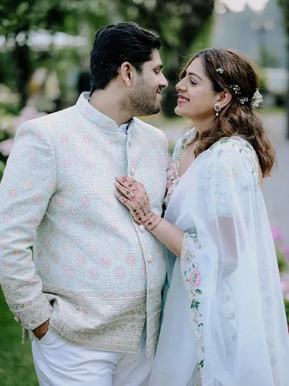 A close-up portrait capturing the loving gaze between the couple during their engagement shoot. The bride's delicate henna and the groom's classic attire are beautifully detailed.