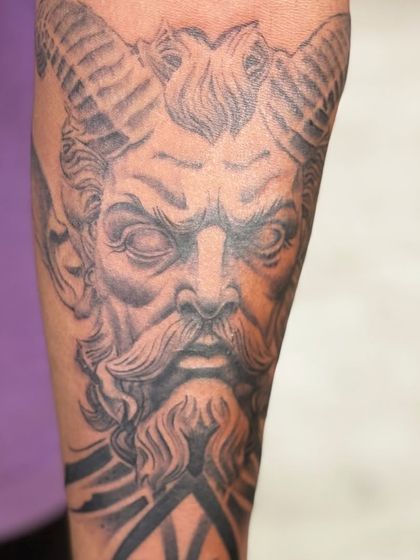 A close-up on the face of the horned god tattoo, highlighting the texture and shading in the beard and horns.