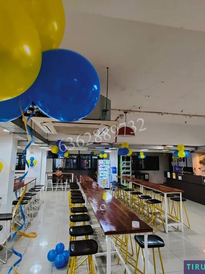 Decorating a large office cafeteria space with big helium balloons for a corporate celebration.