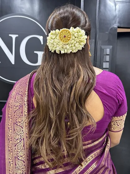 A beautiful half-up, half-down hairstyle perfect for a wedding reception or sangeet. We styled her hair with soft waves and added a traditional gajra with a decorative centerpiece for an elegant touch.