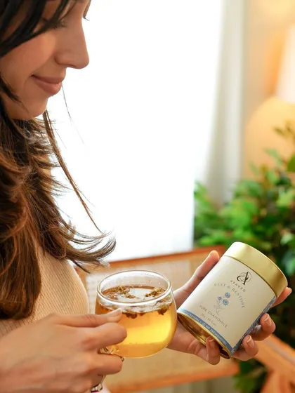 A lifestyle shot capturing a moment of self-care, with a woman holding a cup of chamomile tea, reinforcing the product's calming benefits.