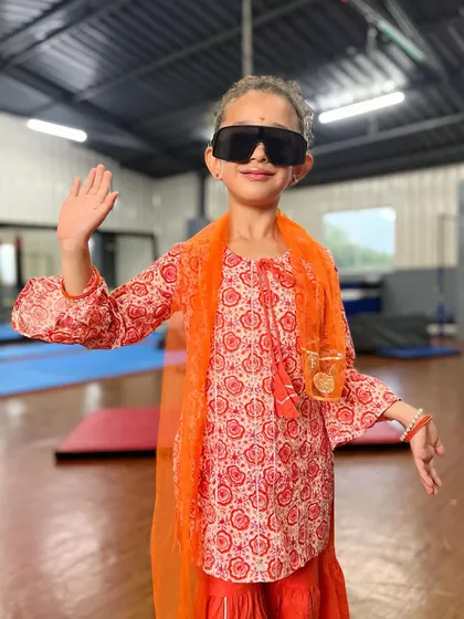 Waving to her fans with superstar style. This little dancer is full of personality, and we're here to help her shine.