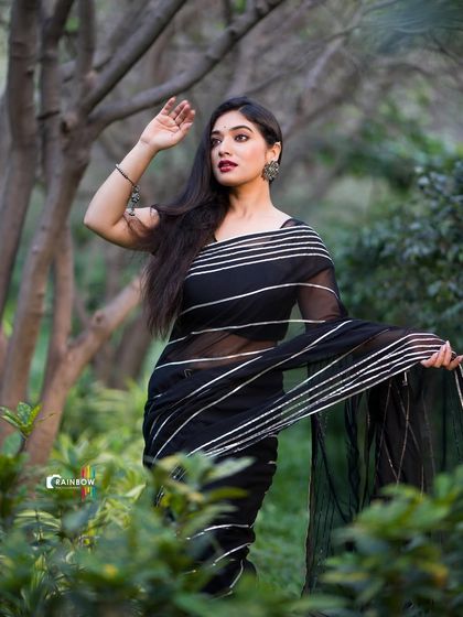 A dramatic pose in a black striped saree, with the model looking over her shoulder.