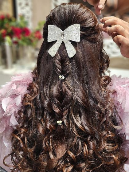 My team and I can create any hairstyle you envision. This bow and braid combination is a perfect example of how we can customize a look to match your personality and outfit.