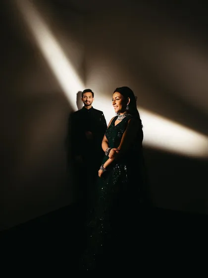 A dramatic and artistic portrait from a Sangeet night. Using a single beam of light, I highlighted the bride in her stunning green outfit while the groom stands in the shadows, creating a moody and cinematic couple photograph.